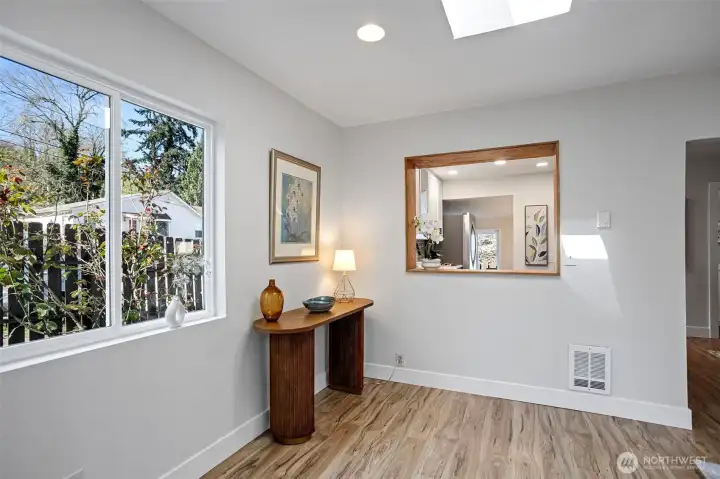 West window to the cobblestone path, wood-framed serve-through to the kitchen — this corner pulls in light and keeps the cook in the conversation.