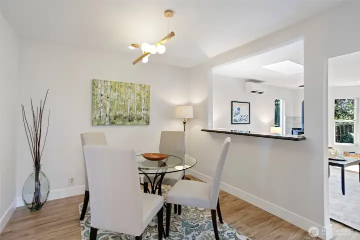 From the dining room, the open passage frames the living room beyond — mini-split, quartz ledge, and light borrowed front to back.
