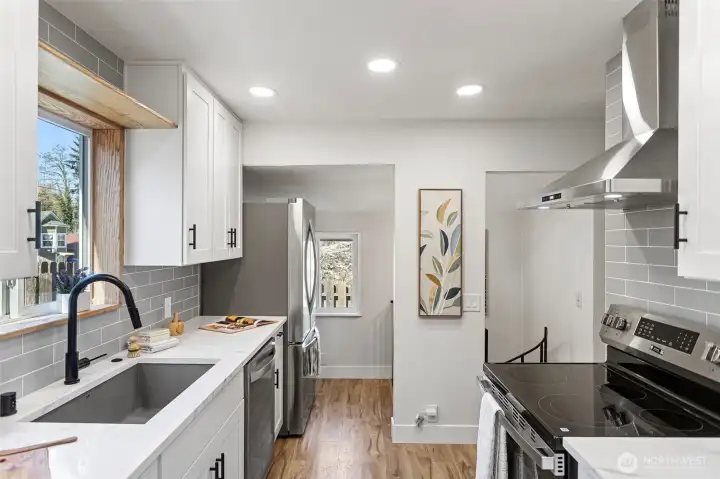 The full run: sink to range, quartz counter to counter — and the spiral staircase in the background is your first hint of what's below.