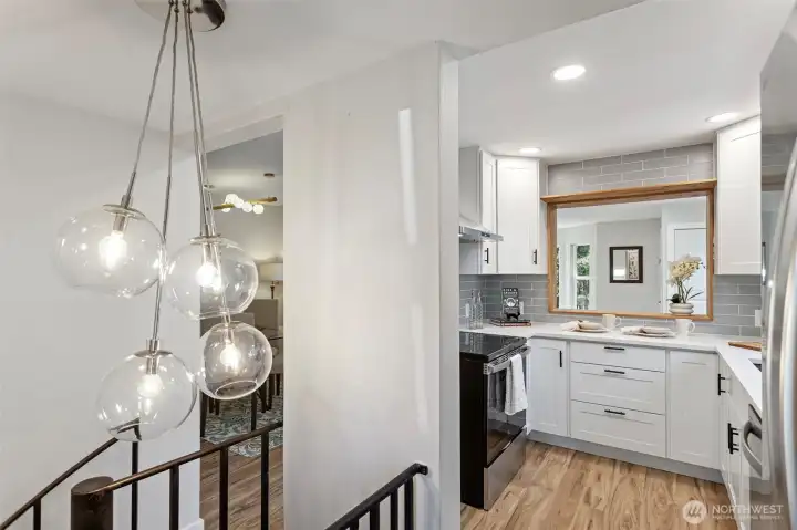 From the spiral stair landing: the globe cluster pendant, the dining room beyond, the kitchen beside it. One last look before the stairs take you down.