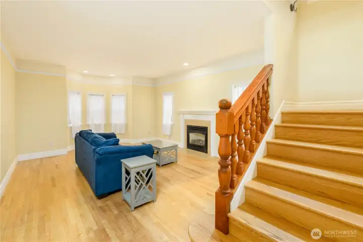 Rich hardwood floors, an elegant staircase, and a cozy fireplace create a warm, inviting living room designed for gathering and making memories. Rich hardwood floors, an elegant staircase, and a cozy fireplace create a warm, inviting living room designed for gathering and making memories.