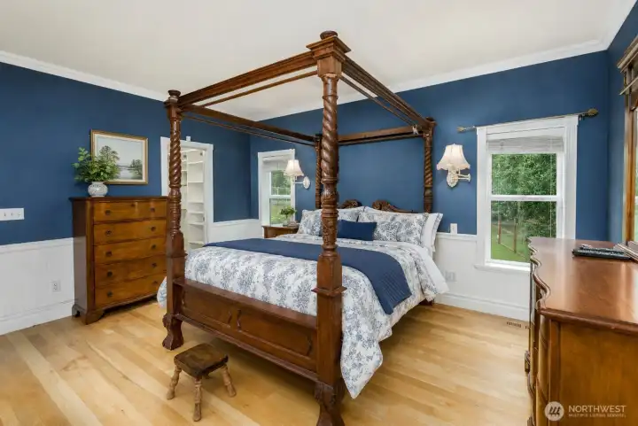 Virtually Staged with bedding-Primary bedroom featuring a walk in closet, rich hardwood furnishings, and elegant wainscoting, creating a timeless retreat with generous space and direct access to the luxurious ensuite bath. Virtually Staged with bedding-Primary bedroom featuring a walk in closet, rich hardwood furnishings, and elegant wainscoting, creating a timeless retreat with generous space and direct access to the luxurious ensuite bath.
