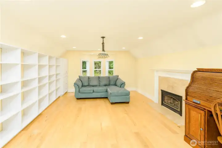 An expansive bonus room offers endless possibilities with built-in shelving, a cozy fireplace, rich hardwood floors, and abundant natural light—perfect as a library, media room, home office, studio, or private retreat. An expansive bonus room offers endless possibilities with built-in shelving, a cozy fireplace, rich hardwood floors, and abundant natural light—perfect as a library, media room, home office, studio, or private retreat.