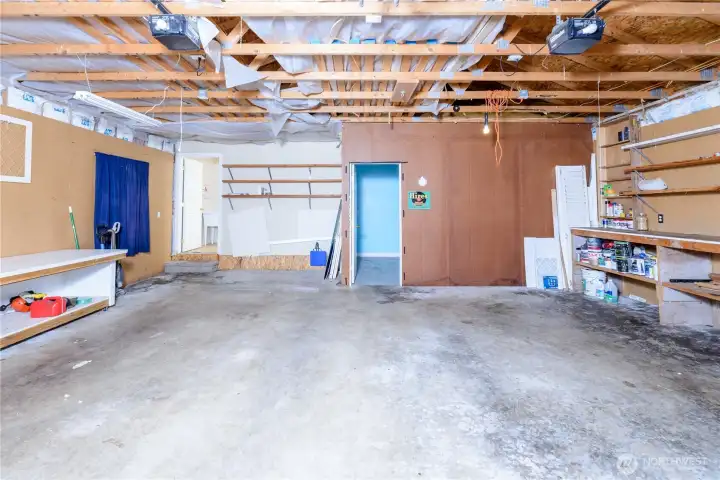 Another view of the detached two-car garage showcasing extensive workbench space, open shelving, pegboard walls, and a dedicated workshop area. Another view of the detached two-car garage showcasing extensive workbench space, open shelving, pegboard walls, and a dedicated workshop area.