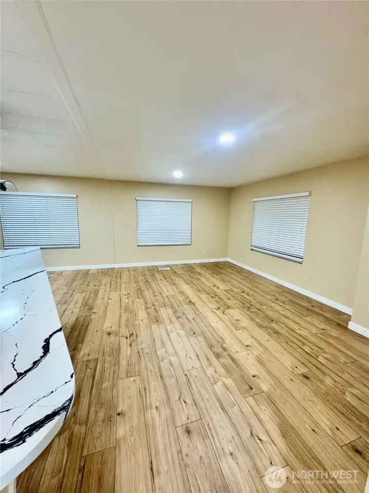 zoomed out picture of the living room with drapes down and laminated hardwood flooring