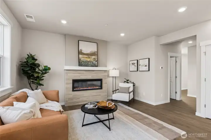 Comfortable living area featuring a cozy fireplace and open layout. Photo shown is staged from a different homesite.