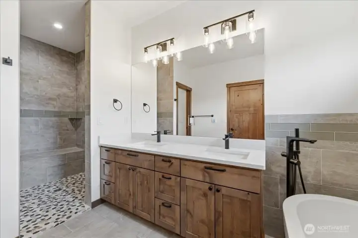 Double vanity with beautifuilly adorned tile work in both flooring and spa like shower with heated floors