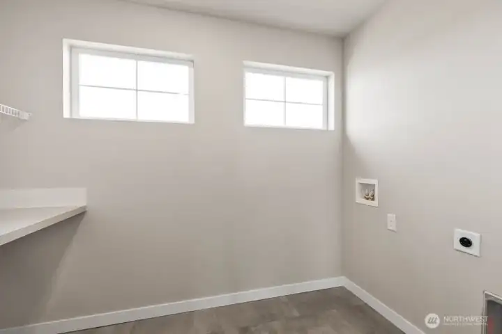 Utility room is conveniently located on the upper floor; Large folding counter across from washer and dryer location. Colors, finishes, and options will vary.