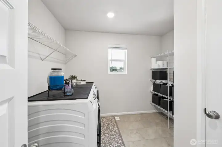 Over sized laundry room with built in shelving, washer & dryer stay.