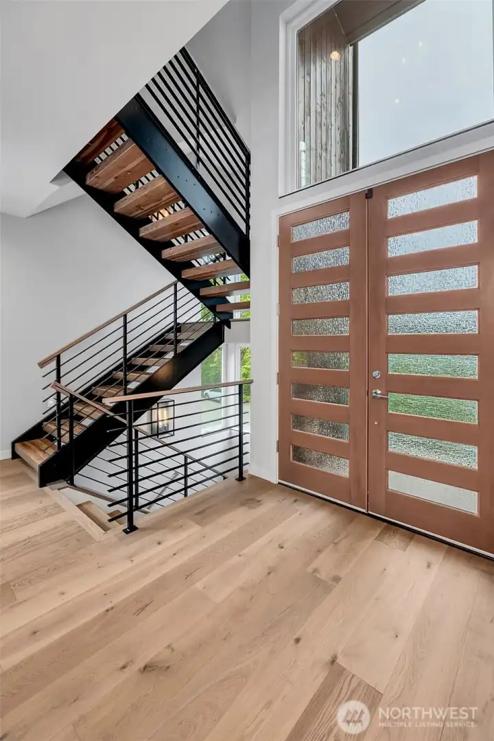 Natural stained front door, white oak wide plank hardwood floors. Dramatic floating stairway with walls of windows Natural stained front door, white oak wide plank hardwood floors. Dramatic floating stairway with walls of windows
