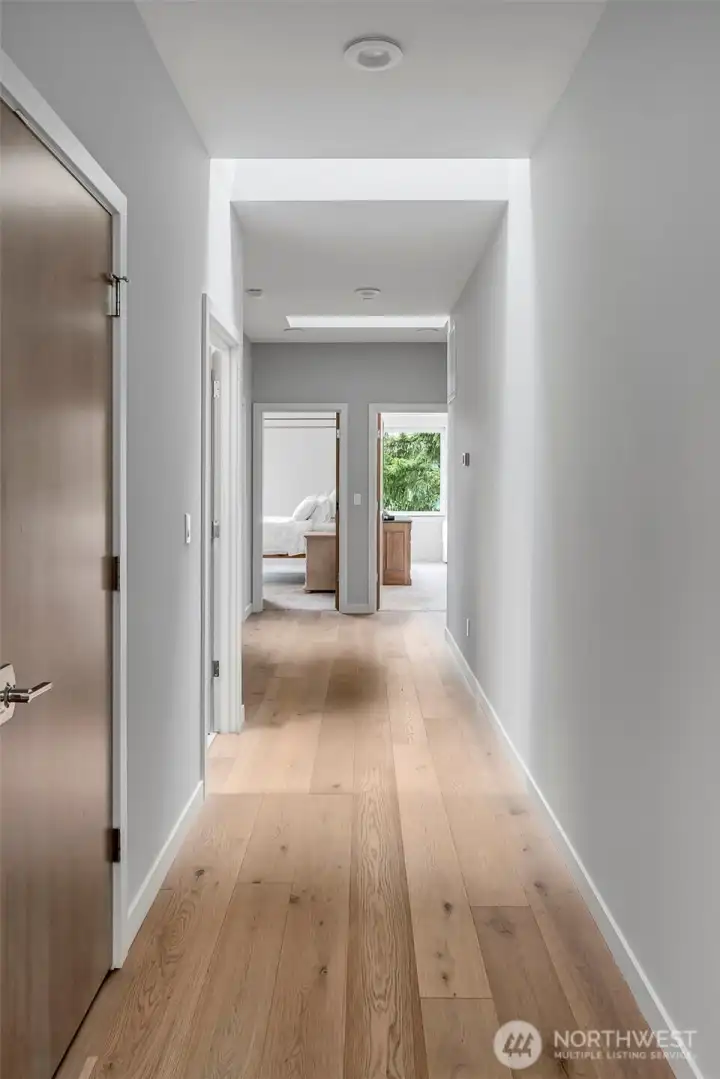 Dramatic upper level hallway with hardwood floors has a series of skylights that allow sunlight to illuminate the space. Dramatic upper level hallway with hardwood floors has a series of skylights that allow sunlight to illuminate the space.
