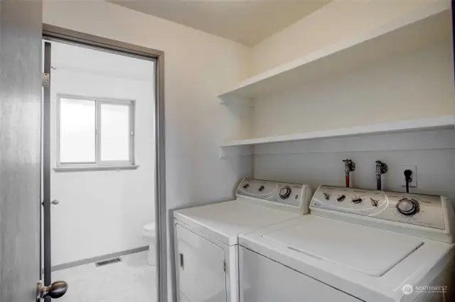 Laundry room with built in shelving and entrance to 1/2 bath