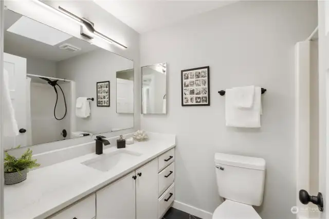 Full/guest bath with New lighting, quartz countertops, tile floor, hardware, fixtures & toilet and resurfaced tub/shower.