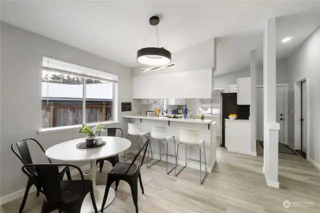 Open dining room adjacent to breakfast bar & kitchen showcasing New flooring, quartz counters, lighting & fresh paint.