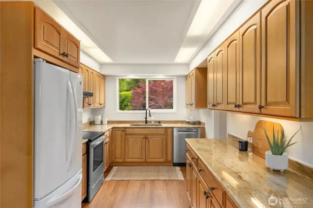 Cozy kitchen with granite counters and a brand new stainless steel dishwasher. Lovely honey colored cabinets warm up the room.