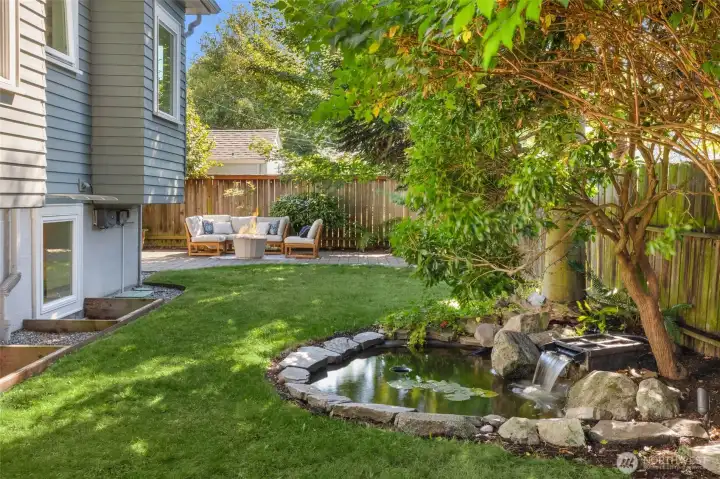 Outdoor sanctuary under mature trees with a level lawn and koi pond.
