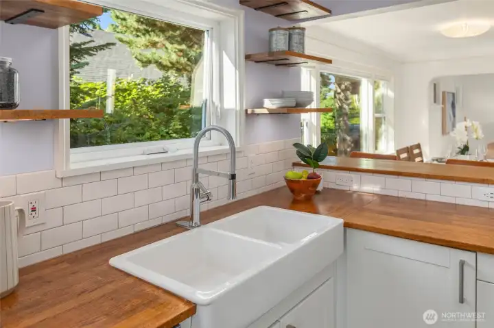 Farmhouse sink overlooking well landscaped yard and pond.
