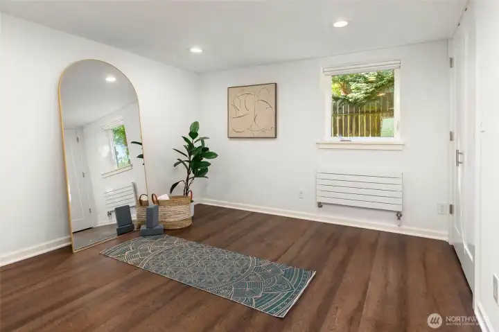 Lower level bedroom with full windows and quiet, efficient Runtal hydronic heaters.
