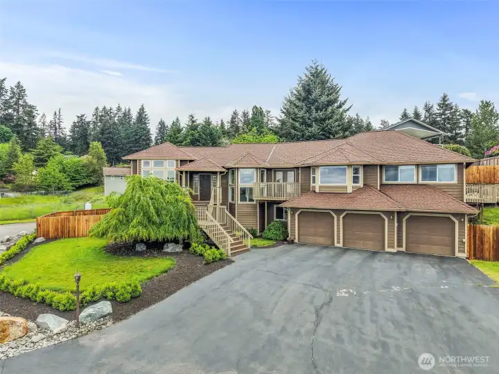 Front exterior with mature landscaping, a wide driveway, 3-car garage, and a fully fenced yard on a dead-end cul-de-sac in Bonney Lake.