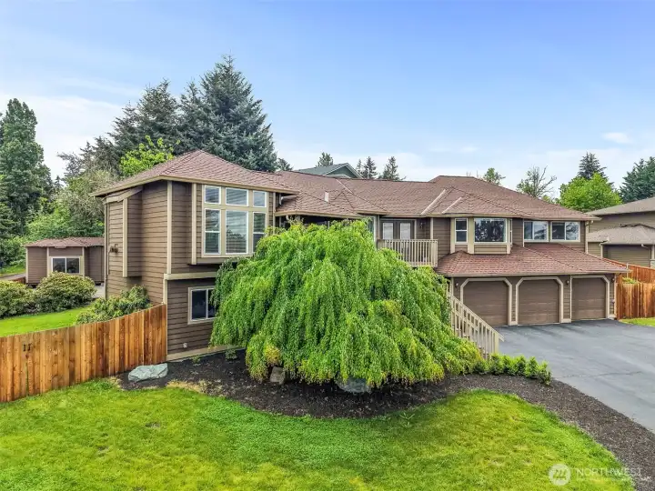 Front exterior with mature landscaping, a wide driveway, 3-car garage, and a fully fenced yard on a dead-end cul-de-sac in Bonney Lake.