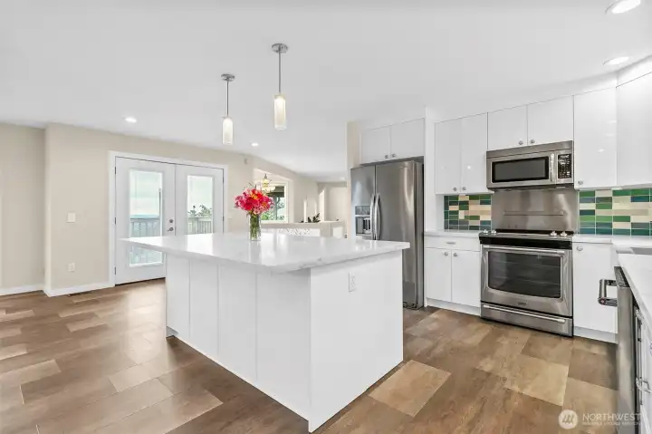 Updated kitchen with quartz counters, stainless appliances, tile backsplash, and a large island for easy prep and gathering.