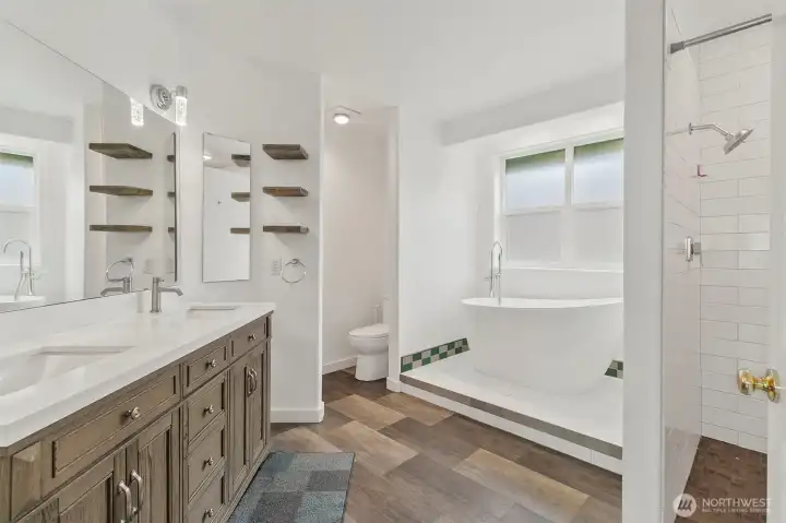 Primary bath with dual vanity, freestanding soaking tub, tiled shower, and bright clean finishes.