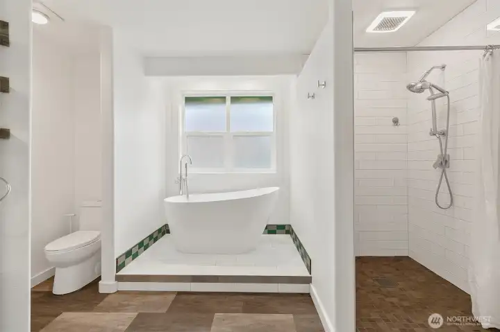 Primary bath with dual vanity, freestanding soaking tub, tiled shower, and bright clean finishes.