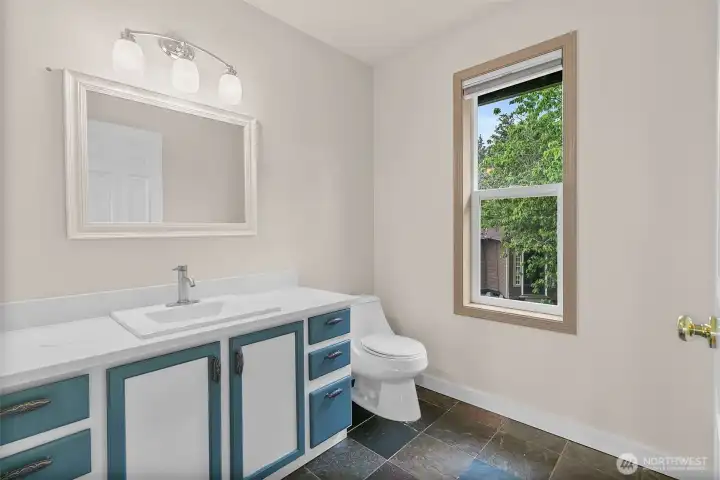 Half bath with updated vanity, window, and tile flooring.
