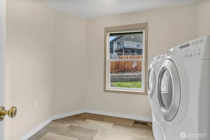 Laundry room with window, washer and dryer, and extra open space for storage or folding.