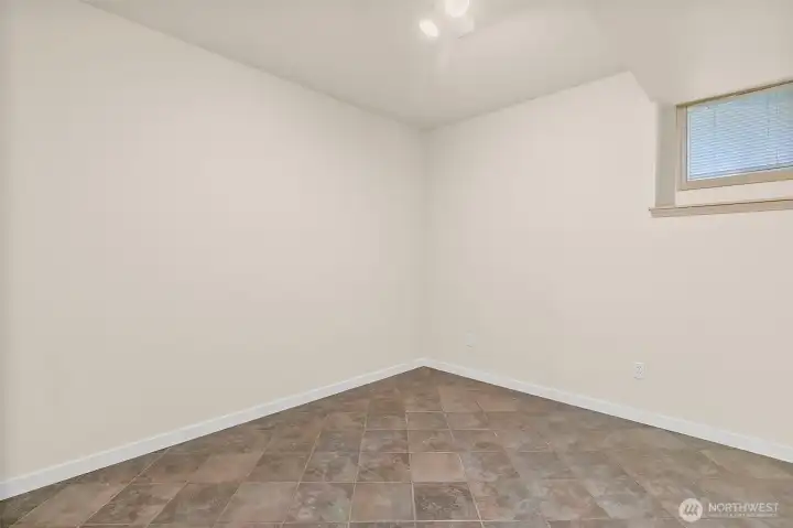 Studio room with window, tile flooring, and flexible space for an office, guest area, or hobby room.