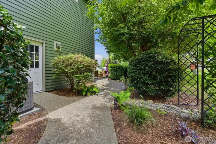 Beautifully designed pathways wind through lush, mature landscaping. A private and welcoming approach to the garage and outdoor spaces
