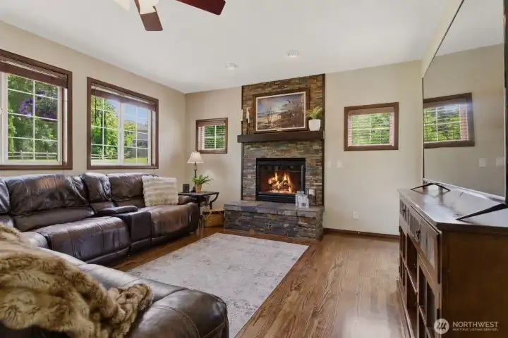 The inviting living room features stunning wood-wrapped windows and a beautiful gas fireplace with dramatic floor-to-ceiling rock surround and rich wood beam mantle