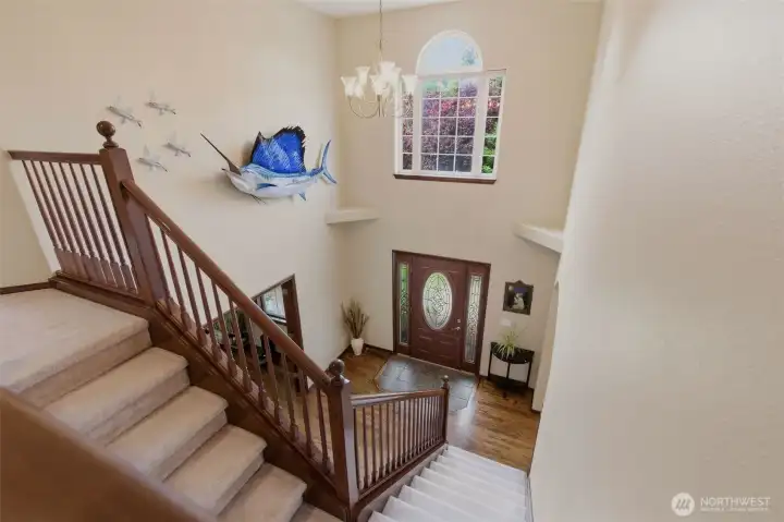 From the upper level, the dramatic view overlooking the grand foyer showcases the home’s soaring ceilings, elegant staircase, and impressive architectural design