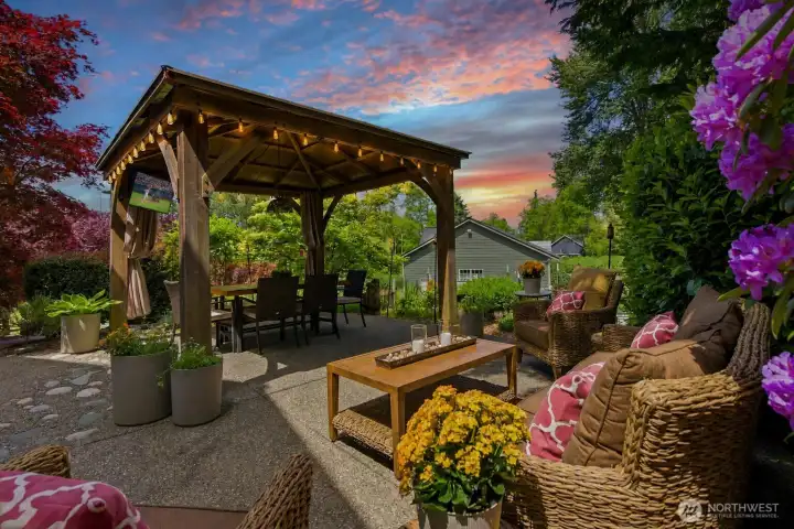 Your own private outdoor retreat — lighted gazebo, outdoor dining, TV lounge area, and lush mature landscaping designed for relaxing and entertaining