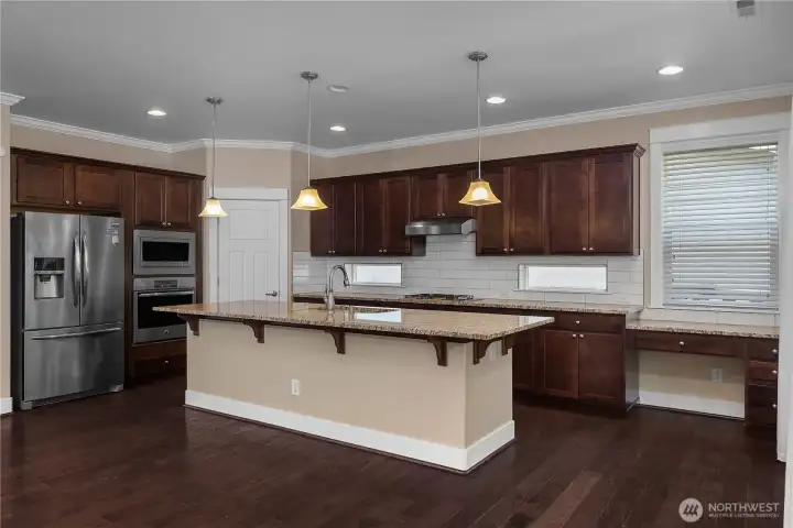 Spacious kitchen with a large granite island, breakfast bar, dark wood cabinetry and stainless steel appliances. Spacious kitchen with a large granite island, breakfast bar, dark wood cabinetry and stainless steel appliances.