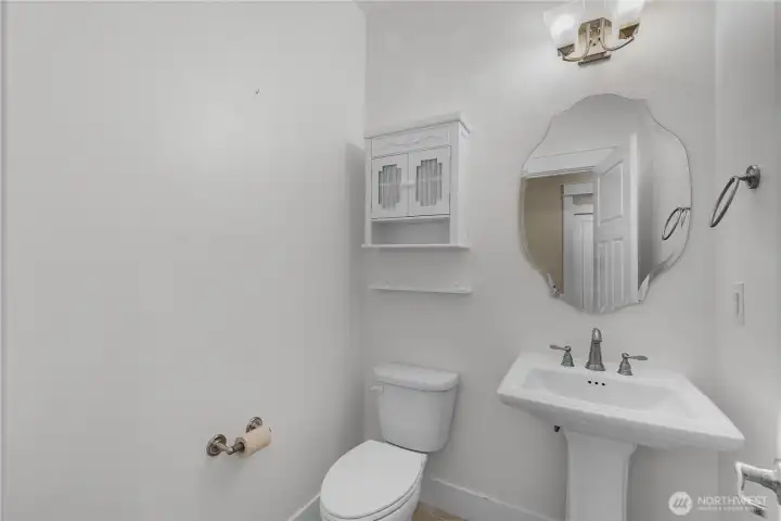 Convenient guest powder room with pedestal sink, decorative mirror and bright neutral finishes. Convenient guest powder room with pedestal sink, decorative mirror and bright neutral finishes.
