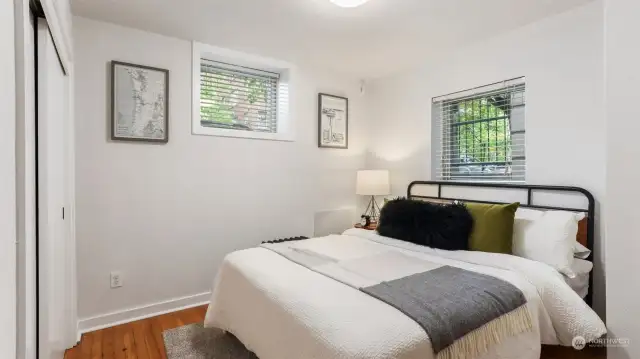 Cozy bedroom big enough for queen bed and nightstands with closet and natural light shining in