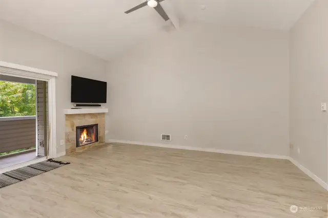 Living room with a brushed nickel finished ceiling fan and light, a wood burning fireplace, a white mantle and sandy colored tile surround.  The Samsung TV and sound bar will remain.