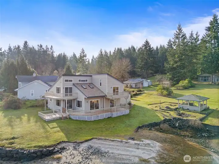 Set on 112 feet of no-bank waterfront with tideland rights, this remarkable property sits on 1.88 acres along Pickering Passage, offering expansive views of the Harstine Island Bridge and Puget Sound. The 2,560 sq ft main home is designed to live like a rambler, with a primary bedroom, laundry, and multiple living spaces on the main level, while nearly every room enjoys water views. An upper-level family room and loft provide additional flexible space. Outdoor decks lead directly to the yard and beach, where currents naturally help maintain the shoreline, and a waterfront gazebo offers the perfect place to relax and take in the scenery.