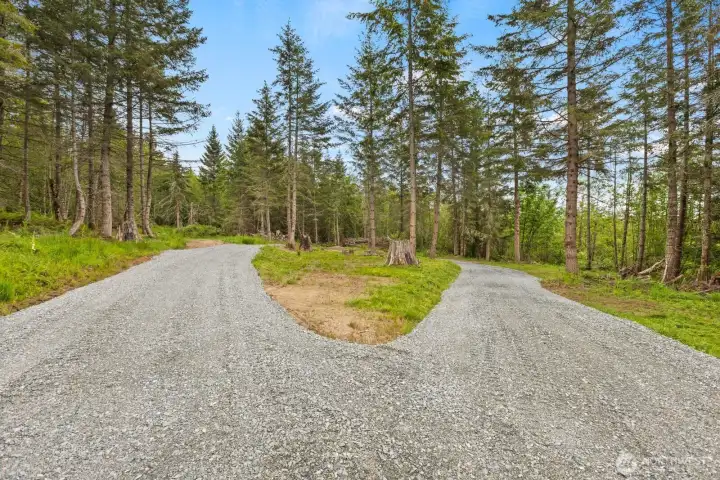 Gated gravel driveway entrance leading into this secluded 10-acre Eatonville property surrounded by mature evergreens.