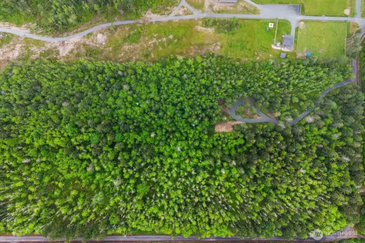 Aerial view showcasing the full 10-acre parcel with wooded surroundings, established access, and neighboring rural properties.