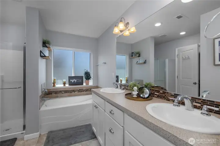 A spacious ensuite features dual sinks abundant counter space, separate shower, & a soaking tub for relaxation.