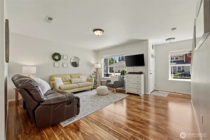 The light-filled living room upon entry highlights the gorgeous laminate wood flooring throughout the main level. The light-filled living room upon entry highlights the gorgeous laminate wood flooring throughout the main level.
