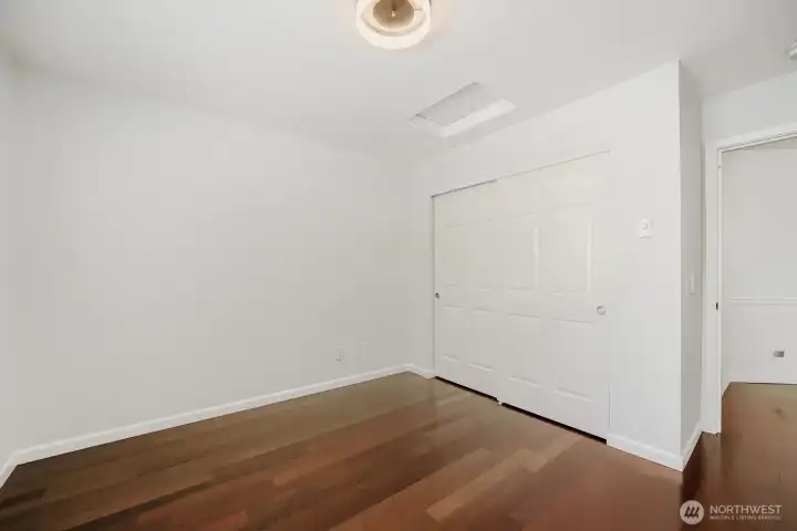Versatile secondary bedroom with rich hardwood flooring and ample closet space.