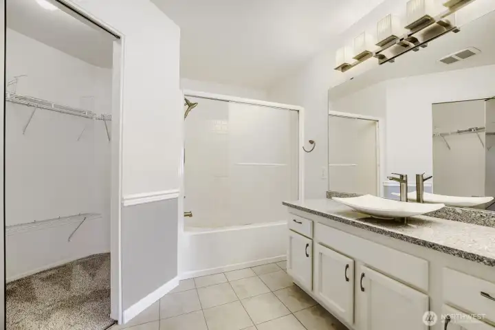Well-appointed ensuite bath featuring dual vessel sinks, abundant counter space, and a walk-in closet.