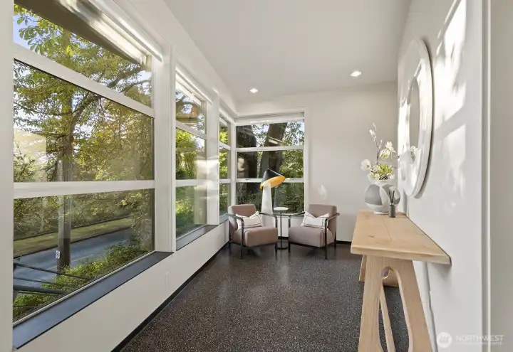 Walls of windows fill the entirety of the home with abundant natural light and tranquil green views.