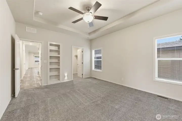 Primary suite features built-in shelving and space for a sitting area or desk, creating a peaceful, personalized retreat.