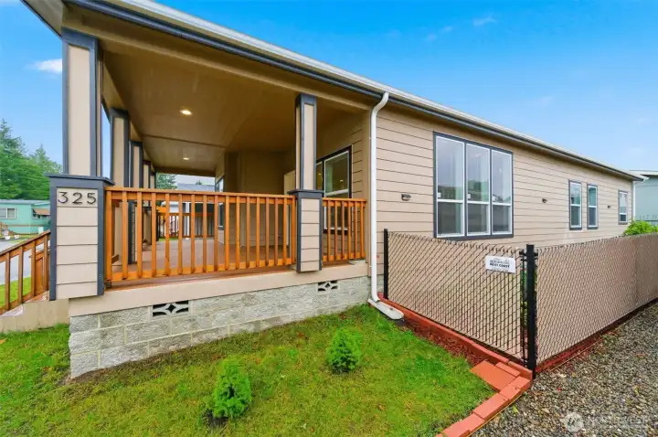 Side view highlights fenced yard space and inviting covered porch, designed for easy outdoor enjoyment.