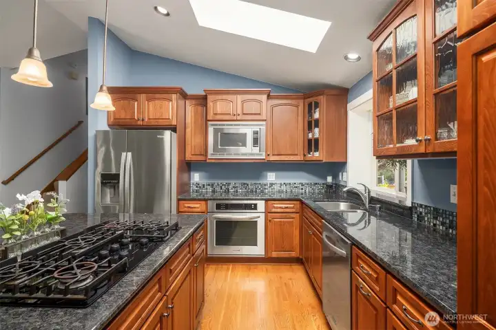 Beautiful custom tilework, 5 burner gas range, convection oven, built-in microwave, dishwasher, and refrigerator. Generous cabinet storage.