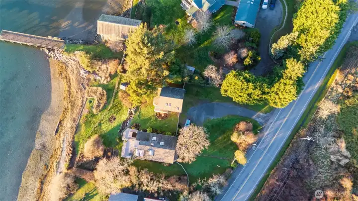 Overhead aerial with 135 ft of waterfront, main house, garage with loft studio, parking, garden, Fisherman Bay Rd on right